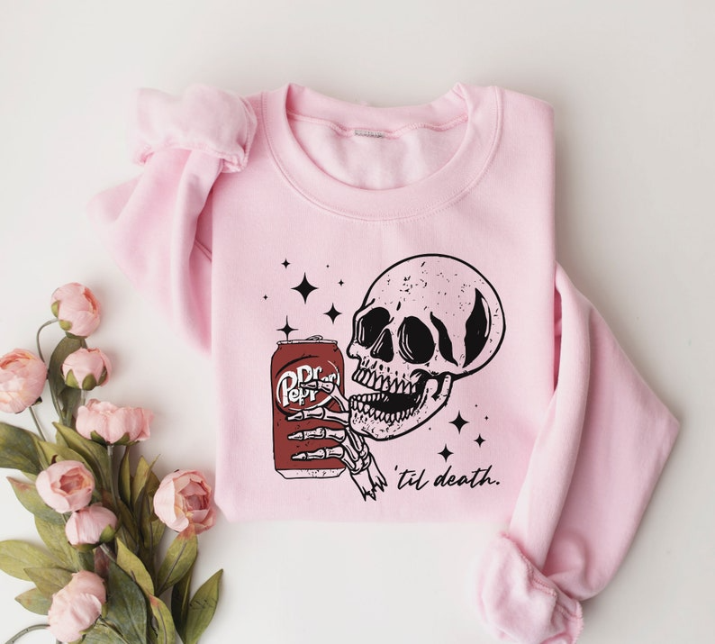 a pink sweater with a skull holding a can of beer