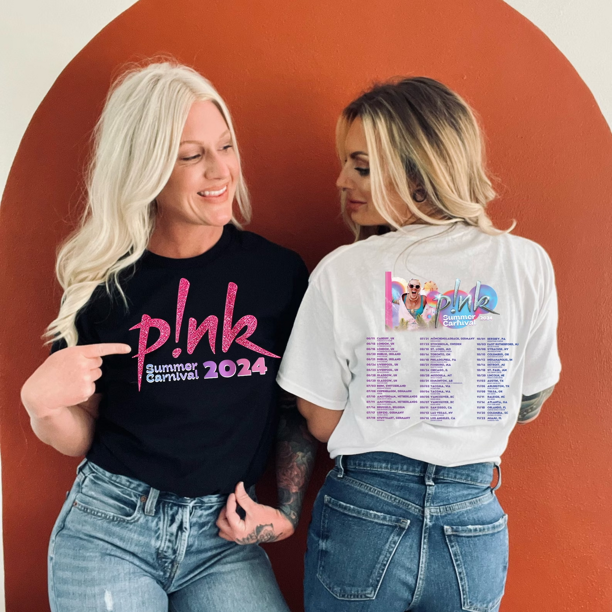 two women standing next to each other pointing at a wall